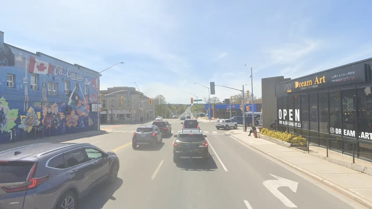Wellington Street East heading west toward Yonge Street in Aurora, past a Canada-themed mural and shops on both sides