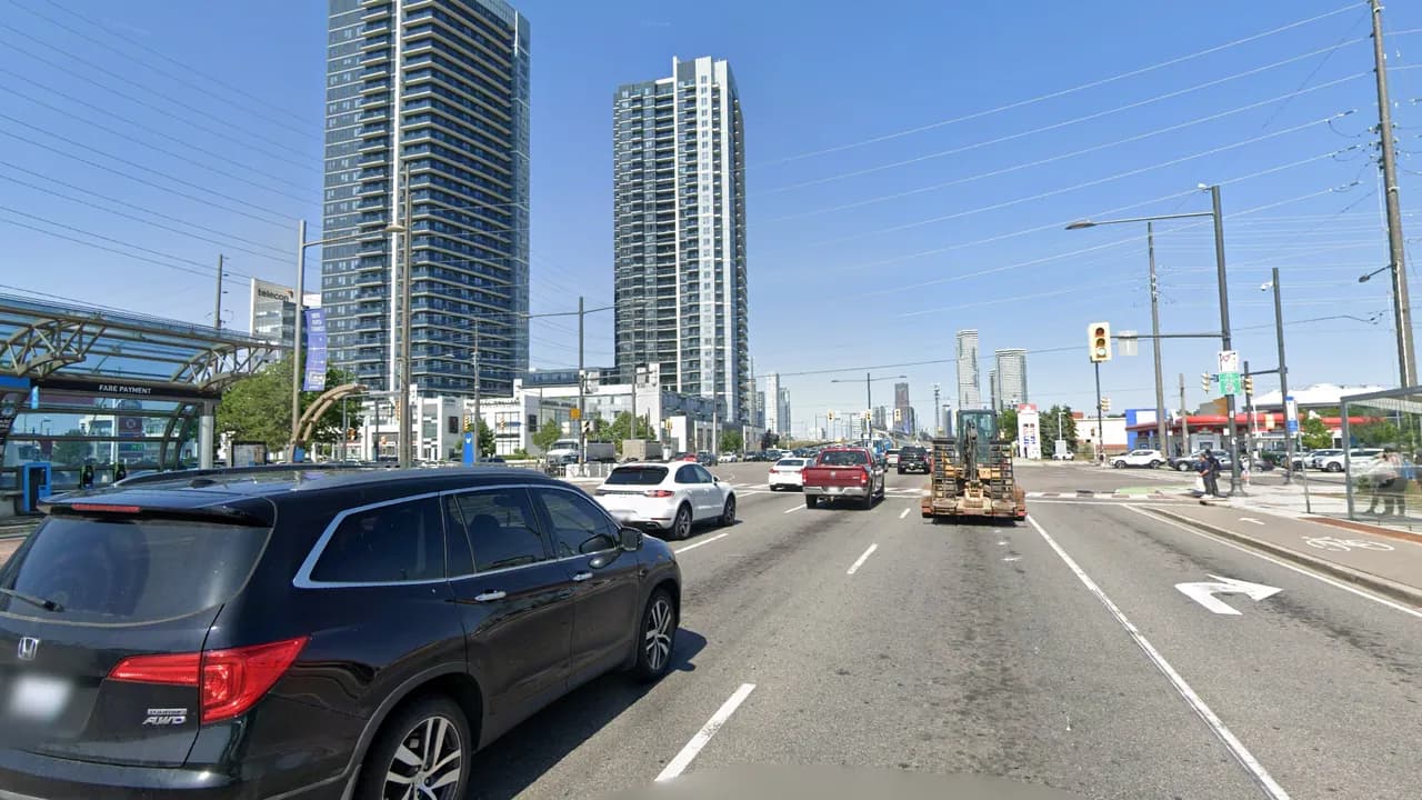 Highway 7 heading east toward Weston Road in Vaughan, with traffic at the light, a Viva station on the left and condo towers beyond