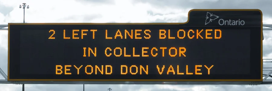Electronic sign over Highway 401 reading 2 LEFT LANES BLOCKED IN COLLECTOR BEYOND DON VALLEY