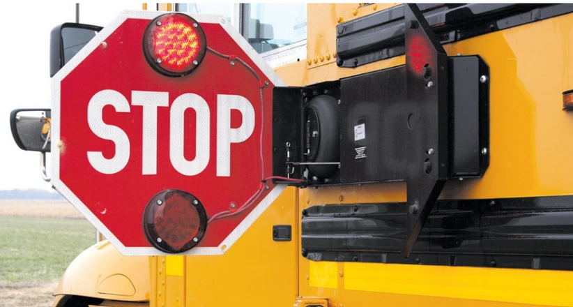 Red STOP arm extended from the side of a yellow school bus